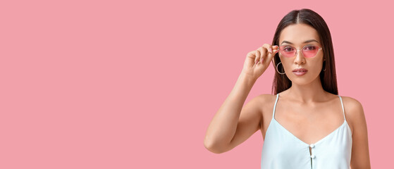 Beautiful young Asian woman with stylish mint makeup in sunglasses on pink background