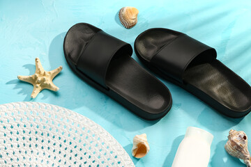 Female stylish flip flops with beach accessories and sunscreen cream on blue background