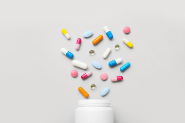 Composition with colorful pills and bottle on grey background