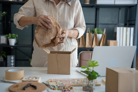 Mature asian woman business E-commerce entrepreneurship owner preparing Packing packages In Cardboard Box to ship to customers. - Powered by Adobe