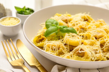 Plate of boiled dumplings with cheese and basil on white background, closeup