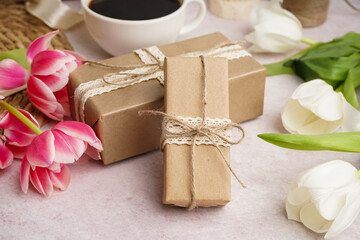 Gift boxes with beautiful tulips and cup of coffee on white background