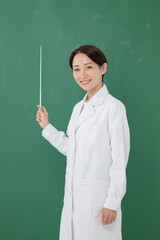 黒板の前に立つ白衣を着た女性