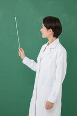黒板の前に立つ白衣を着た女性