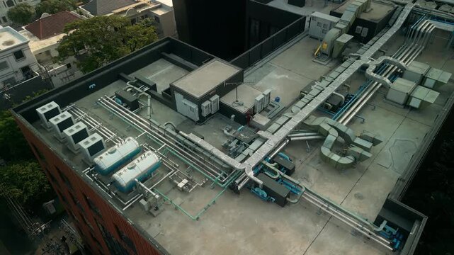 Detailed top-down view of rooftop HVAC layout including air conditioning units, tanks, ducting and insulated piping. Urban engineering solution for climate control on high-rise building.