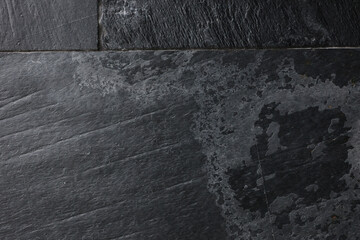 A wall made of dark grey stone slabs.