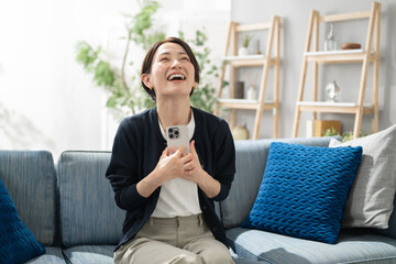 リビングでスマホを使うミドル女性