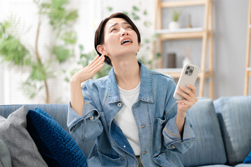 リビングでスマホを見る女性