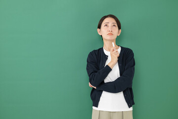 黒板の前で悩む女性