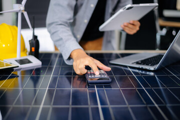 Engineer pointing on solar panel table with tablet and wind model, symbolizing clean energy, innovation, and smart technology for future sustainable development.