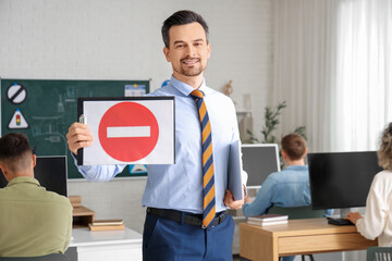 Male instructor with road sign at driving school