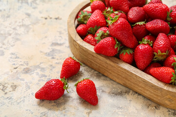 Wooden tray with sweet fresh strawberries on grunge background