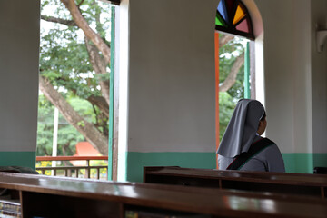 Christian nuns with white robes praying in a church.