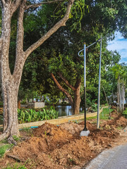 Digging holes to install new solar street light poles to use solar energy as alternative energy source in public park. View of newly solar cell electric pole in emergency condition standing along road