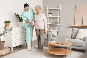 Senior woman with stick and physical therapist walking at home