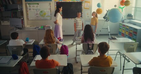 STEM Class on Renewable Energy: Elementary School Students Talking about Energy Sources in Front of Classroom Full of Classmates and Female Teacher. Diverse Children Studying Ecology and Science. - Powered by Adobe