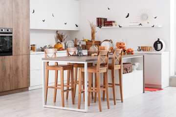 Interior of light kitchen decorated for Halloween with counters, table and pumpkins