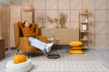 Young woman resting in armchair at home on autumn day