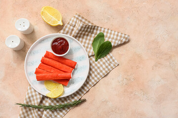 Plate with tasty crab sticks, slices of lemon and bowl of sauce on beige background © Pixel-Shot