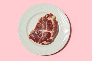 Plate with fresh raw steak on pink background