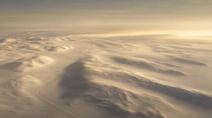 Aerial view of snow-covered mountains shrouded in mist at dawn.
