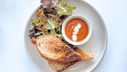 grilled cheese sandwich served with fresh vegetables and sauce on a white plate
