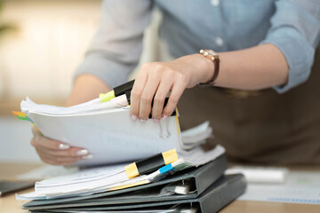 Organized Workspace. Businesswoman sorting through paperwork with colorful tabs.