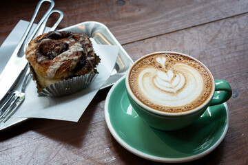 Hot coffee latte with latte art milk foam in cup mug and Homemade Cinnamon Rolls on wood desk on top view. As breakfast In a coffee shop at the cafe,during business work.