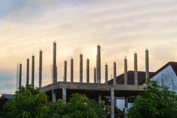 construction site of a multi-storey building in progress, showing scaffolding, brick walls, concrete columns structural in house construction sites blue sky air with golden clouds sunset background