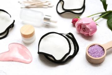 Cotton pads, flowers, guasha and bath supplies on light background