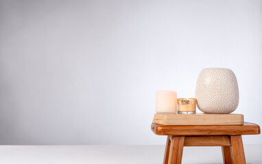 Decorative candles and a ceramic holder on a wooden stool creating a calm ambiance in a modern space