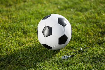 Soccer ball and whistle on green stadium grass