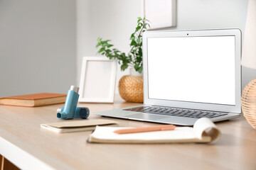 Modern inhalers, notebook and laptop on workspace desk, closeup