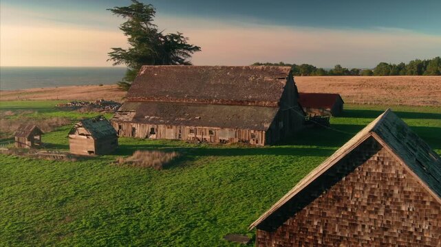 Aerial view of a barn and outbuildings on a farm in  Mendocino, California, USA. The buildings are surrounded by green grass and trees.