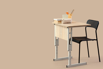 Modern school desk with books, pencil case and stationery on beige background