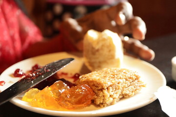 Traditional Caribbean Breakfast Plate with Fresh Bread, Fruit Jam, Golden Marmalade and Sweet Coconut Treat – Authentic Island Cuisine Close-Up Captured in Natural Light