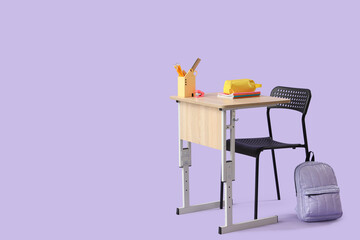 Modern school desk with backpack, pencil case and stationery on lilac background