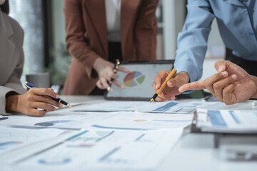 Entrepreneurs, marketers, managers, and financial analysts gather around the table to analyze data,...