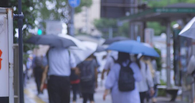 A slow motion of walking commuters on the city street in Tokyo rainy day