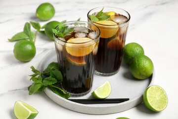Glasses of cold Cuba Libre cocktail with mint and limes on white background, closeup