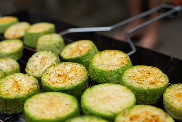 Chopped zucchini and khachapuri roasting on fire seasoned with aroma herbs and spices. Delicious fresh vegetables vegetarian grilling on barbecue smoker grid. Diet vegan bbq. Outdoor recreation in