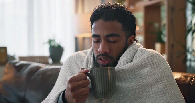 Sick man, blanket and cold with tea on sofa for influenza, virus or flu symptoms in home. Male person, viral infection or shiver with cup, mug or herbal drink for warmth, illness or fever in house