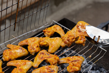 BBQ picnic time Roasted chicken legs and wings on grill. Grilling meat on outdoor grill grid tasty barbecue chicken steak with smoke flames juicy meat in the backyard in summer