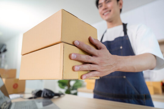 Package handling. Young man lifting boxes for shipping in modern workspace.