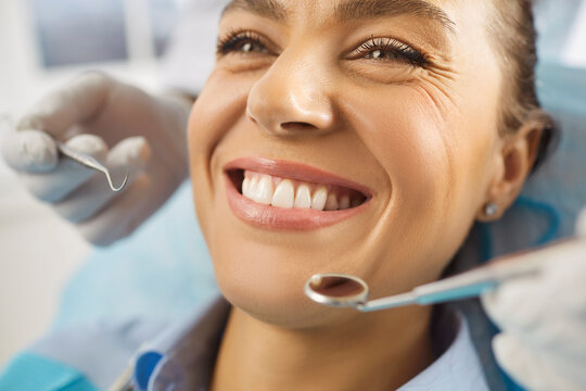 Close up shot of cheerful young woman being on dentist visit, undergoing dental treatment in medical clinic, demonstrating white perfect teeth. Dental care, hygiene and oral cavity concept 