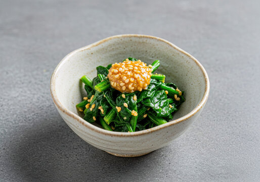 Nutritious Japanese Horenso Gomae: Blanched Spinach with Sweet Toasted Sesame Dressing, Served in a Rustic Ceramic Bowl on a Grey Background