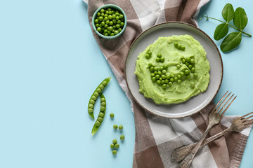 Plate with mashed green peas on blue background