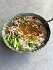 Pho Bo Vietnamese soup, bowl of fresh asian soup with rice noodle, beef meat, herbs, soy sprouts and chili, top view. Asian cuisine.