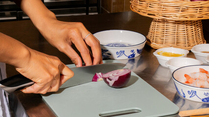 A South Asian woman deftly slices a purple onion, invoking Lunar New Year cuisine and culinary craftsmanship rituals