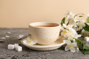 Cup of hot jasmine tea with flowers on grey table